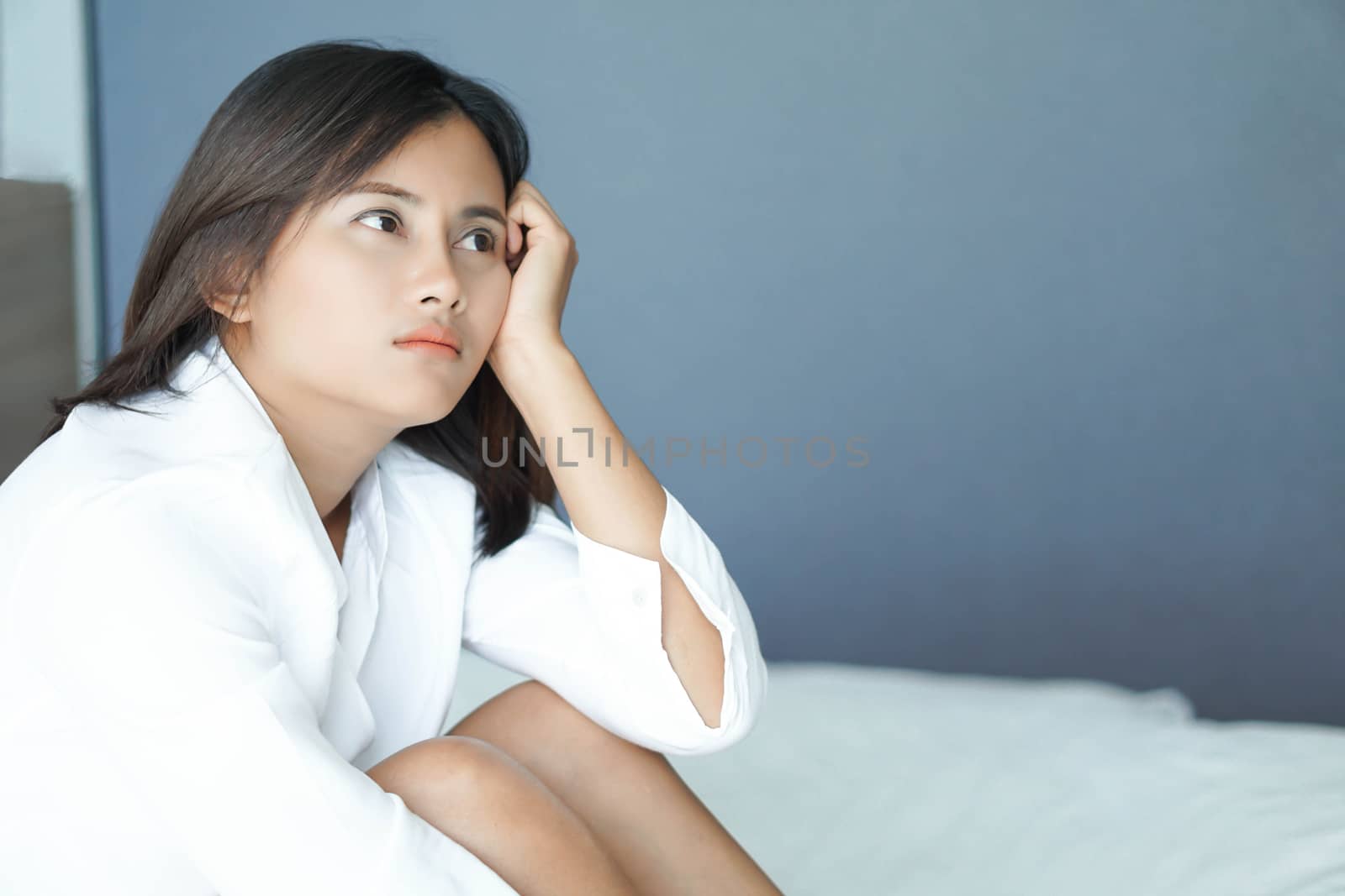 Closeup woman sitting on bed in the bedroom with thinking or depressed feeling, selective focus