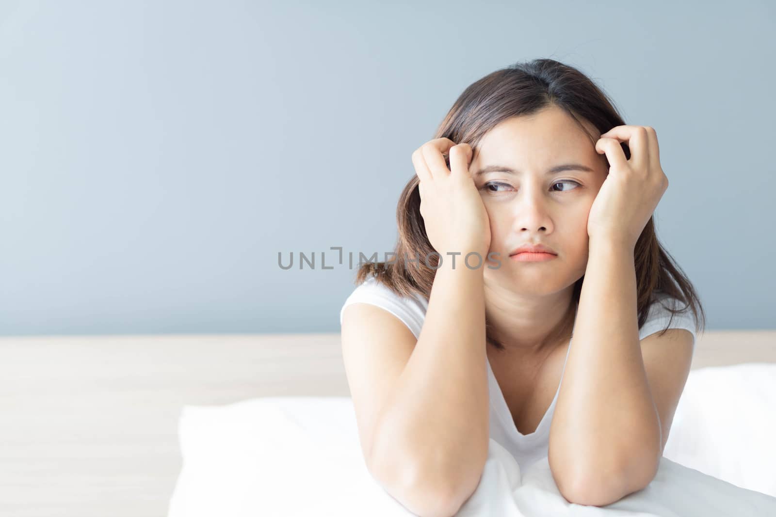 Closeup woman sitting on bed in the bedroom with thinking or depressed feeling, selective focus