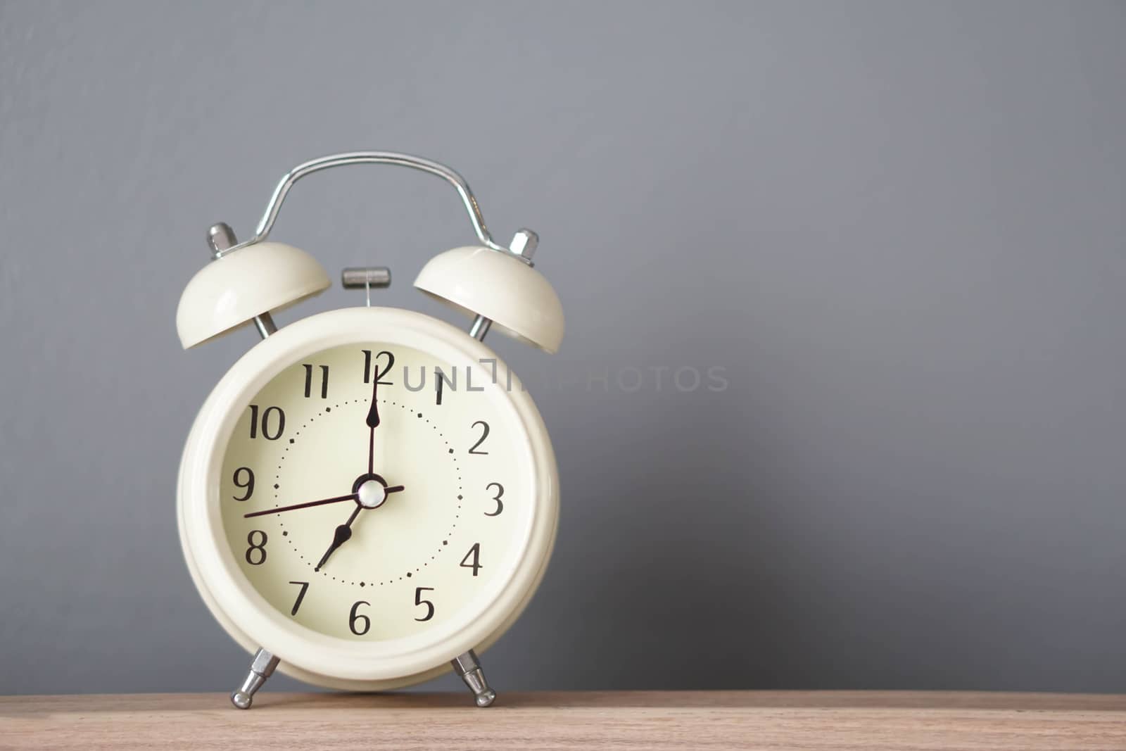 Alarm clock on wooden table with grey background, selective