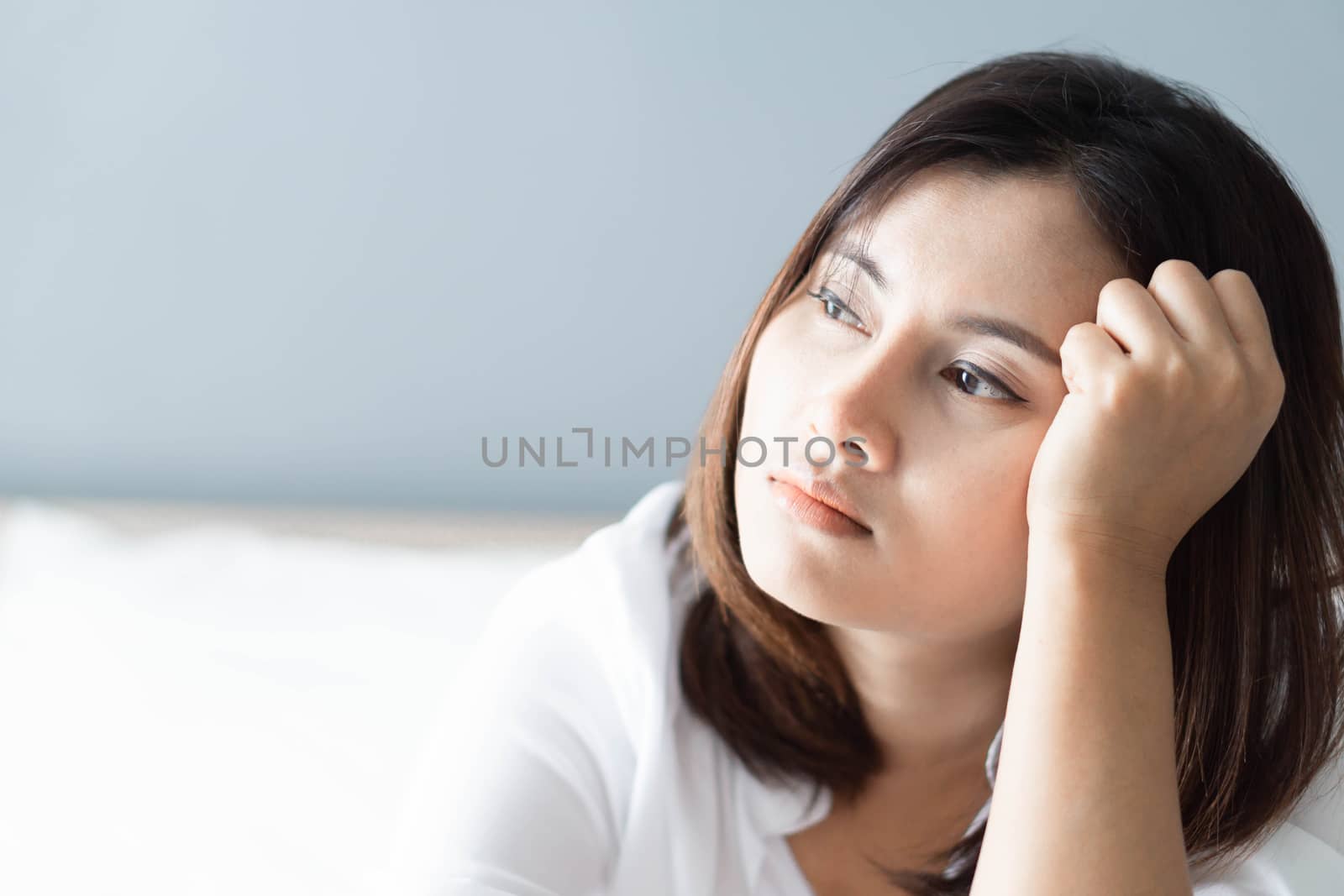 Closeup woman sitting on bed in the bedroom with thinking or depressed feeling, selective focus