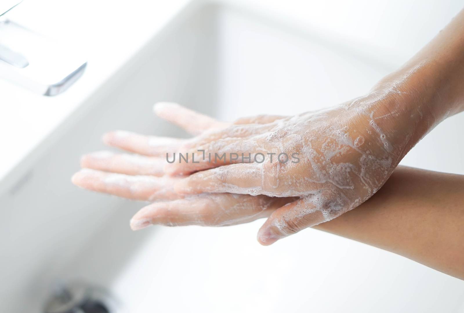 Closeup woman's hand washing with soap in bathroom, selective focus