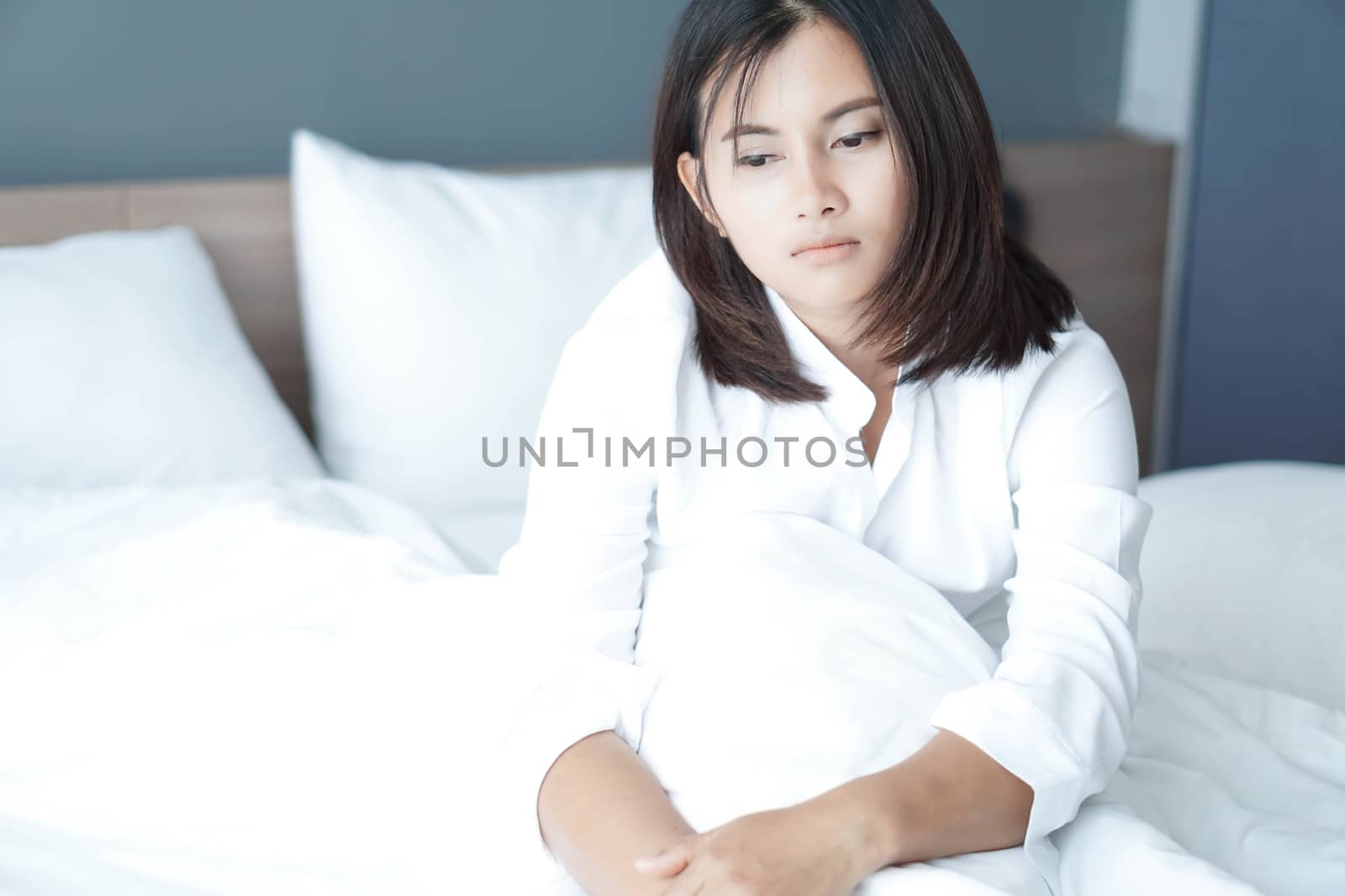 Closeup woman sitting on bed in the bedroom with thinking or depressed feeling, selective focus