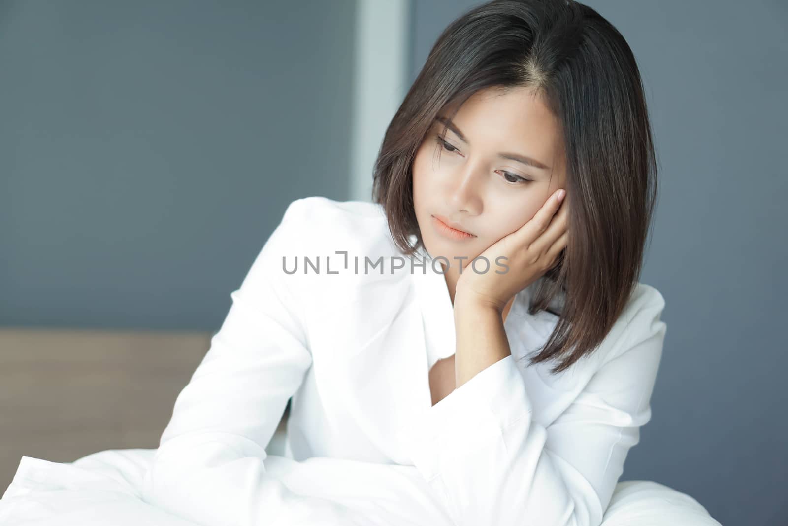 Closeup woman sitting on bed in the bedroom with thinking or depressed feeling, selective focus