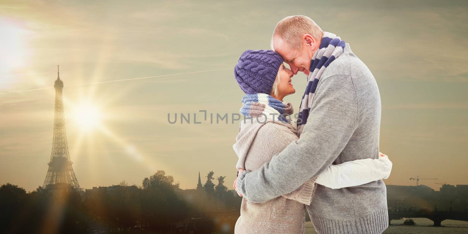 Happy mature couple in winter clothes hugging against eiffel tower