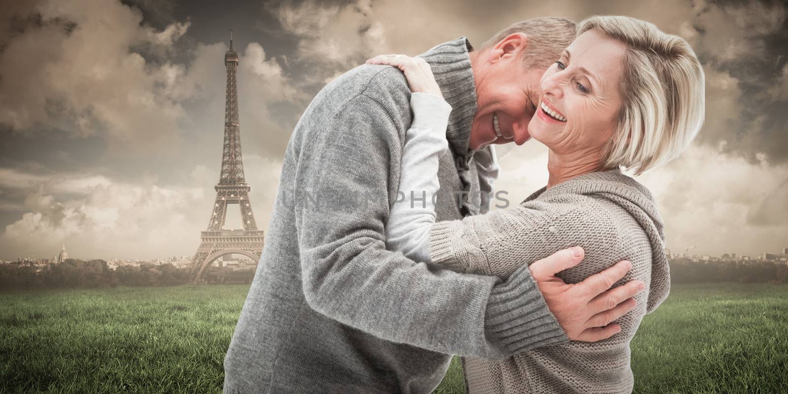 Happy mature couple in winter clothes against paris under cloudy sky