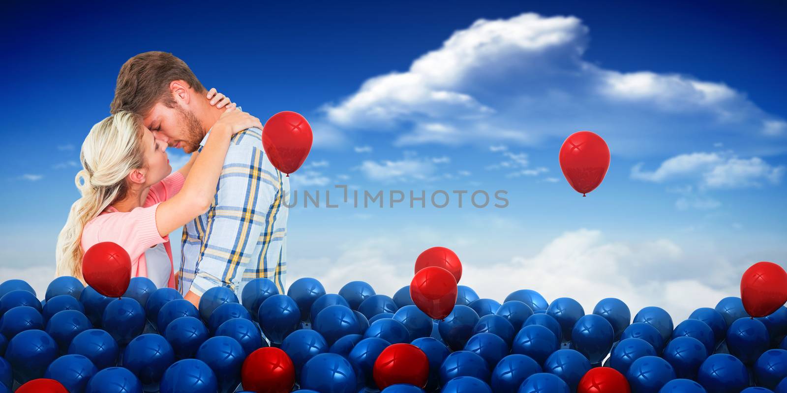 Attractive young couple about to kiss against bright blue sky with clouds