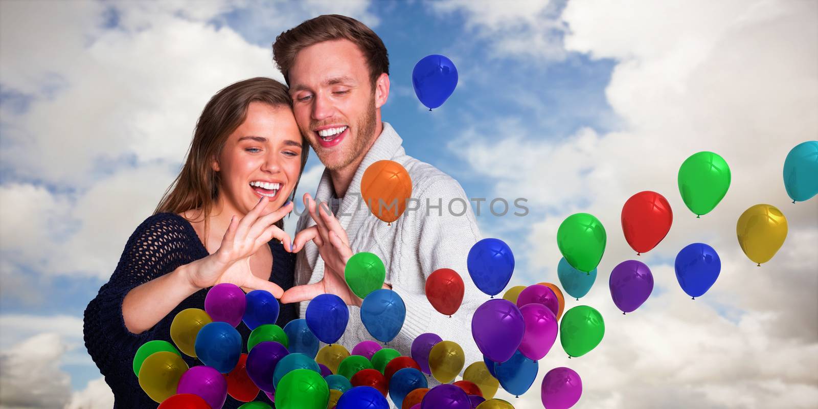 Happy couple forming heart with hands against blue sky with white clouds