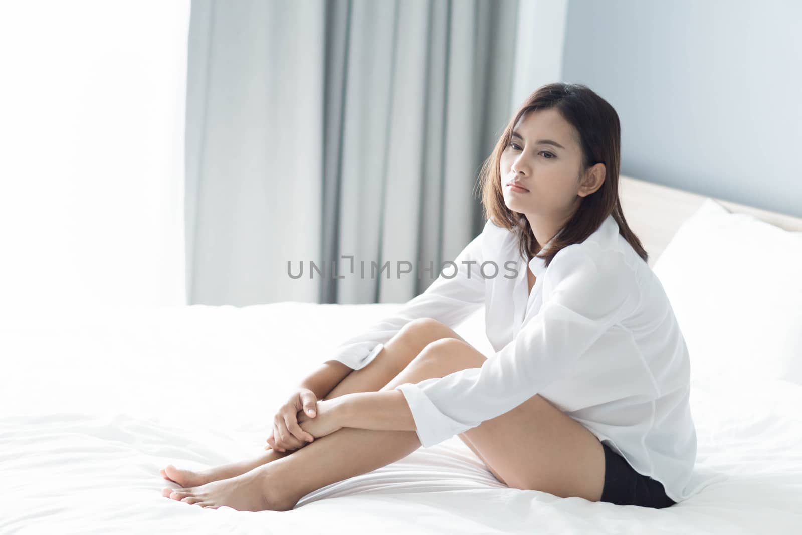 Closeup woman sitting on bed in the bedroom with thinking or depressed feeling, selective focus