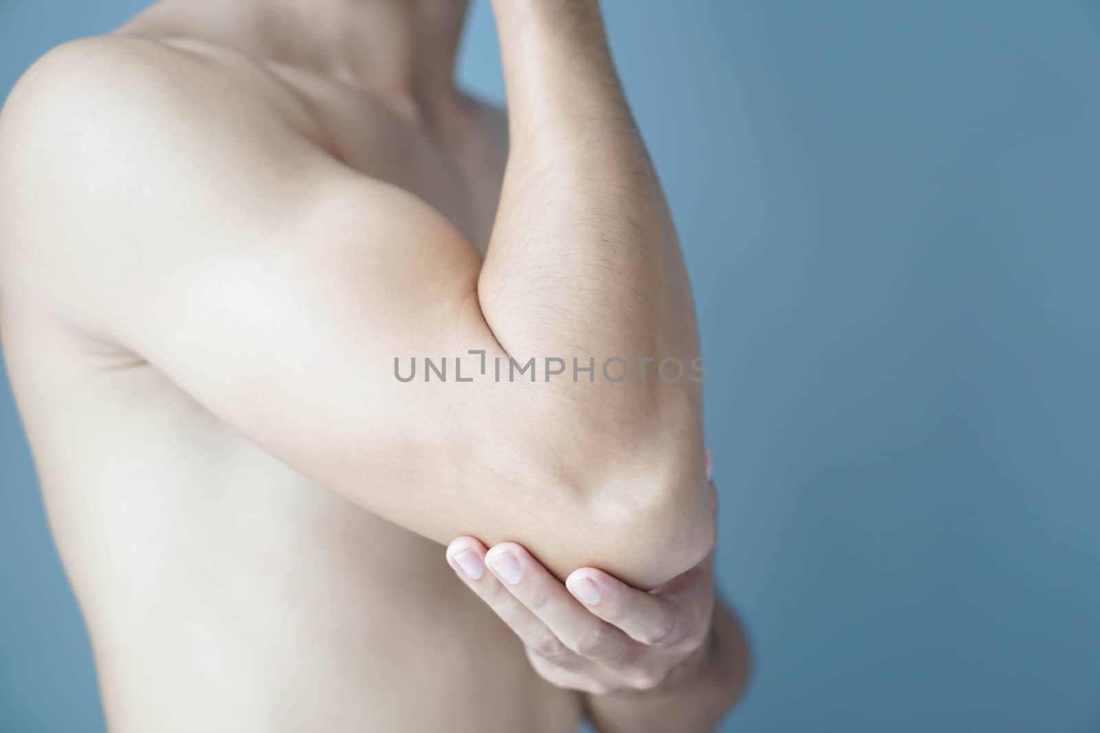 Closeup man hand holding elbow with pain with blue background, health care and medical concept