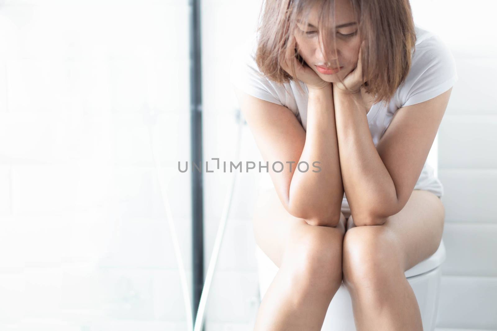 Closeup woman sitting on toilet in the morning with depressed feeling, selective focus