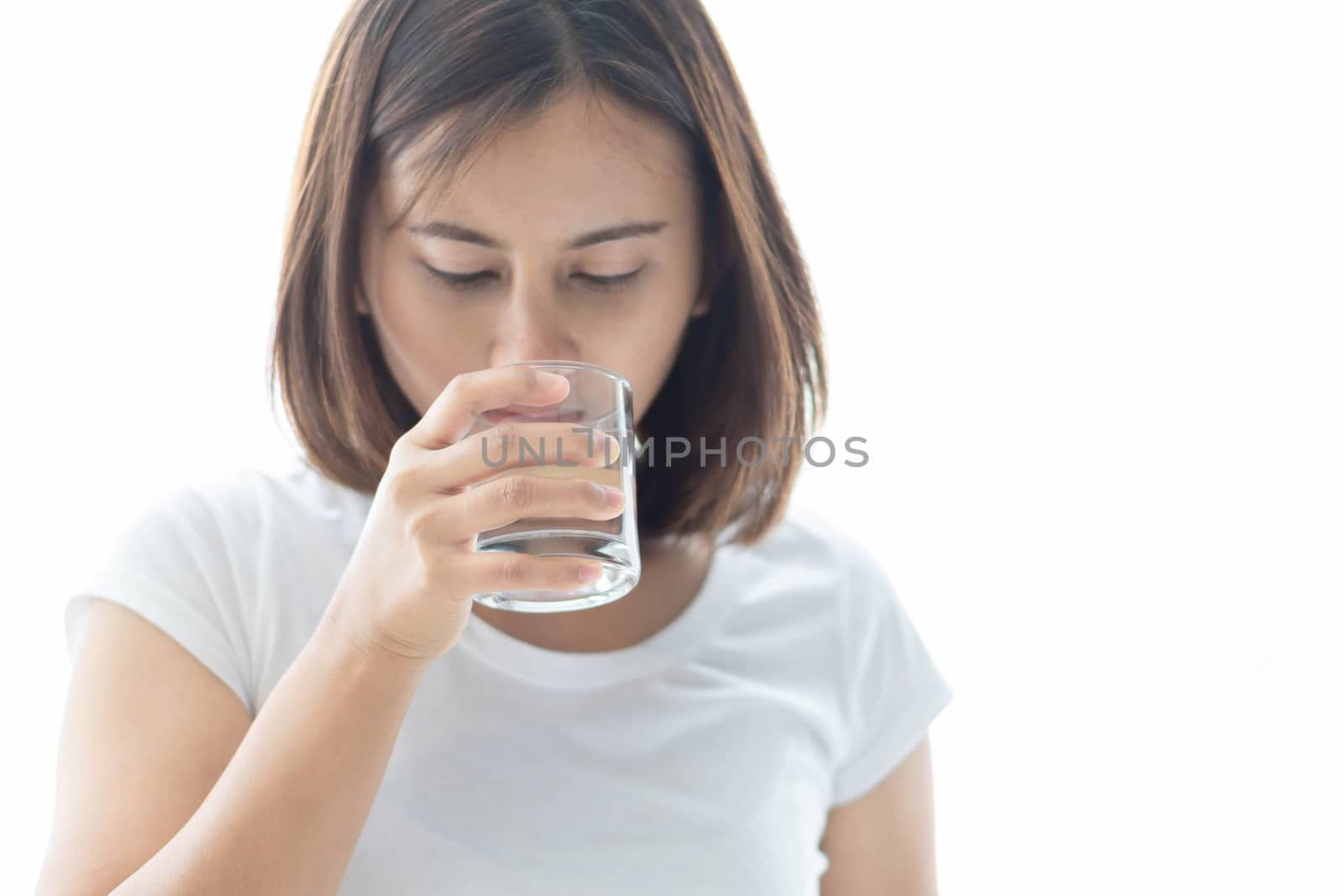 Close up woman drinking pure water from glass with light in the morning, Selective focus