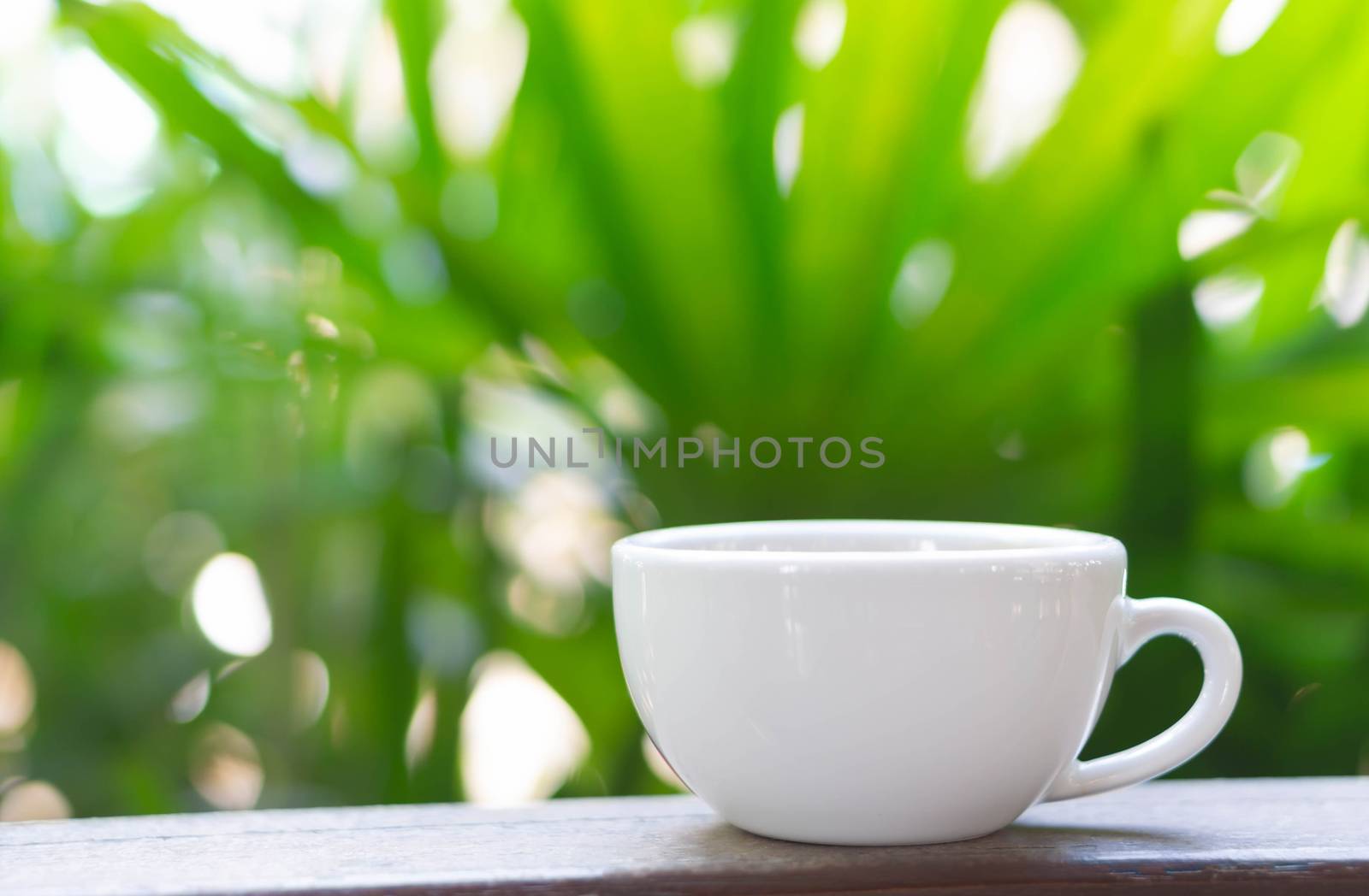 Closeup hot americano coffee on glass table with green nature background