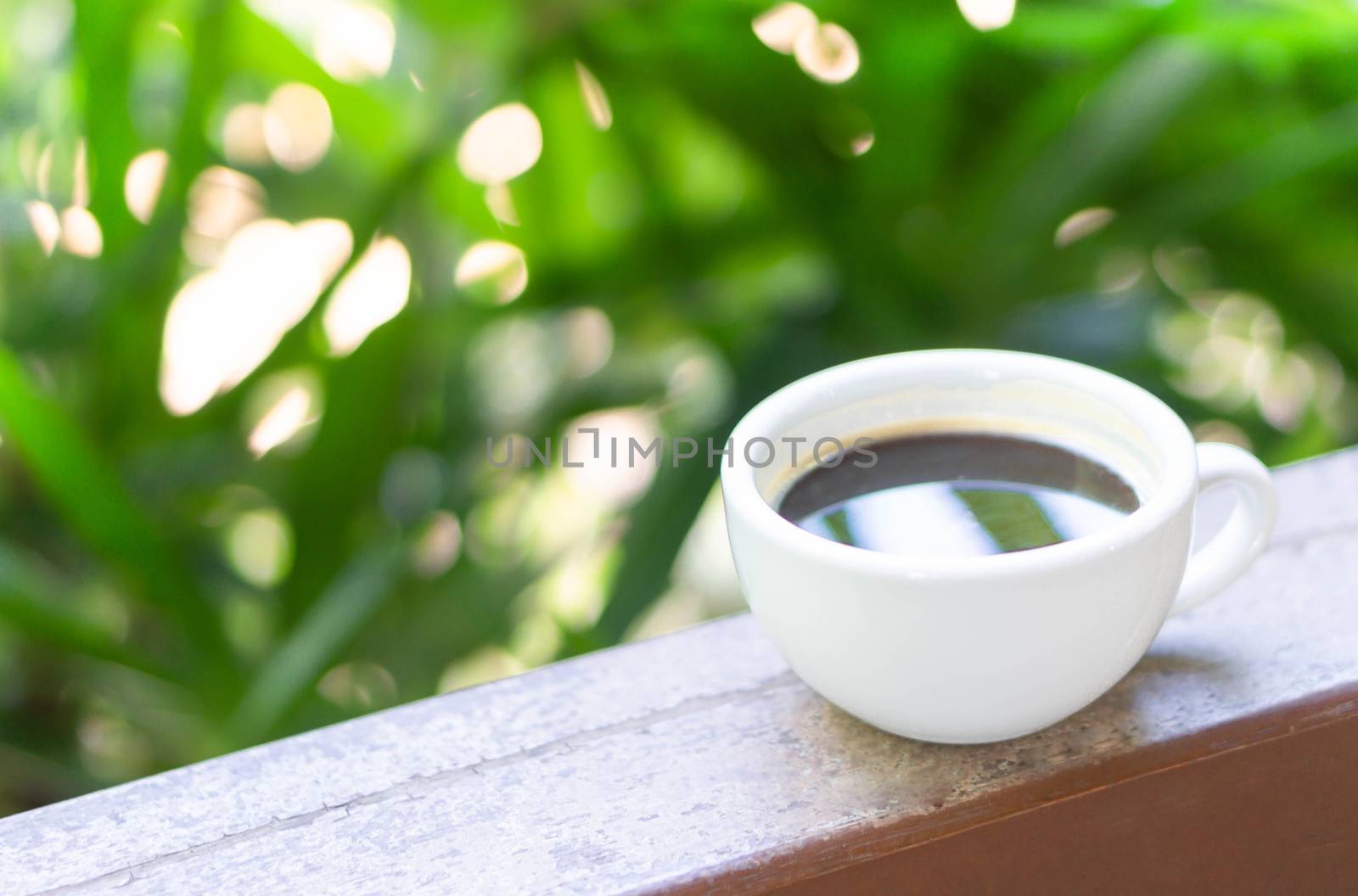 Closeup hot americano coffee on glass table with green nature background