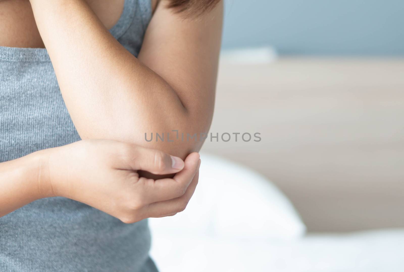 Closeup woman hand holding elbow with pain lying on bed, health care and medical concept