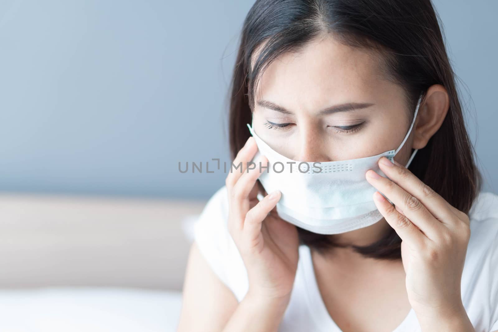 Close up sick woman wearing medical mask face lying on white bed, health care and concept