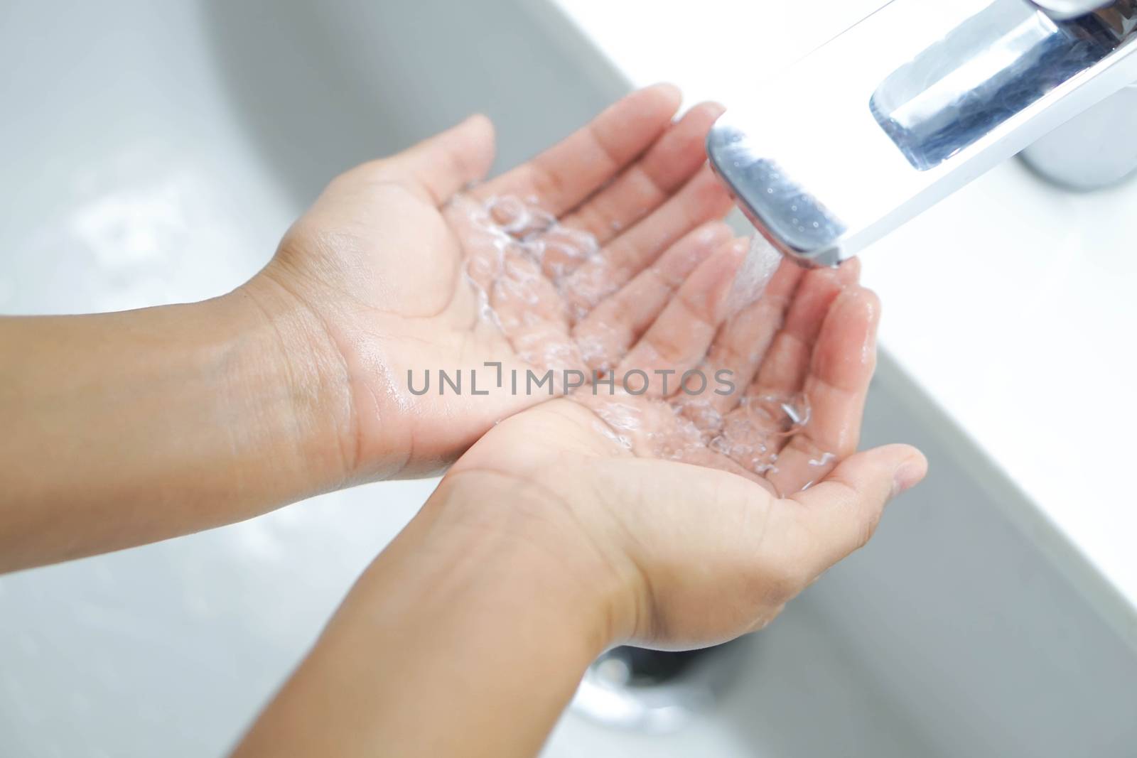 Closeup woman's hand washing with soap in bathroom, selective focus