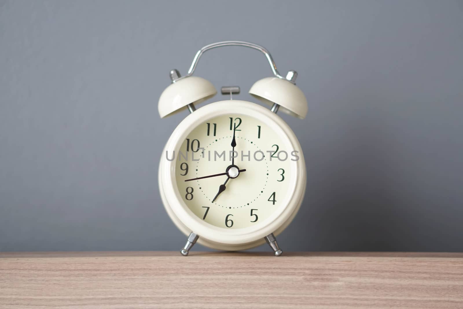 Alarm clock on wooden table with grey background, selective