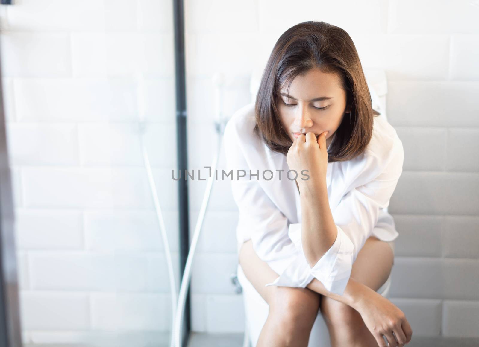 Closeup woman sitting on toilet in the morning with depressed feeling, selective focus