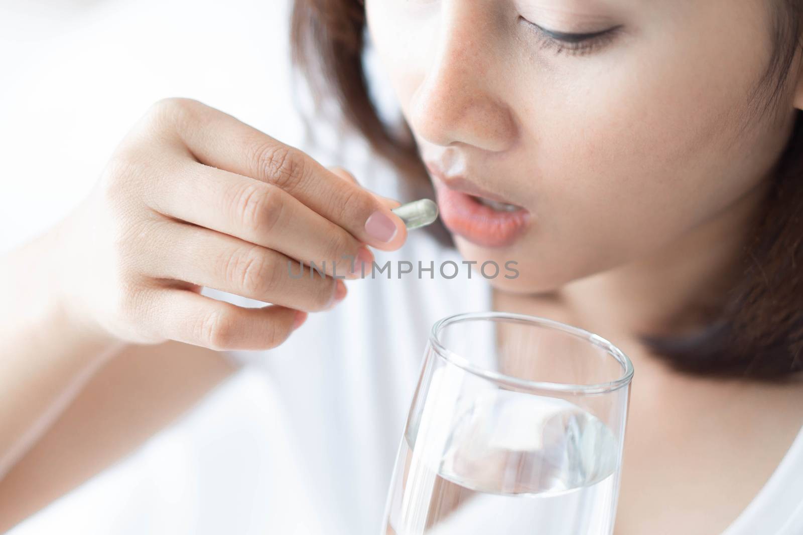 Closeup woman hand holding pills and glass of water, health care and medical concept, selective focus