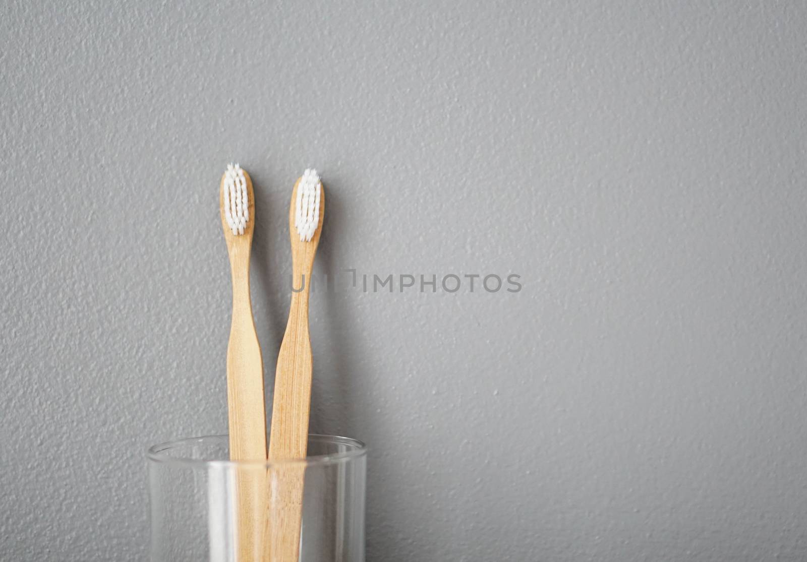 Close up wooden toothbrush in glass with grey background, selective focus