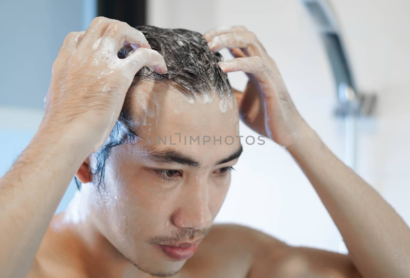 Closeup young man washing hair with with shampoo in the bathroom, vintage tone, selective focus