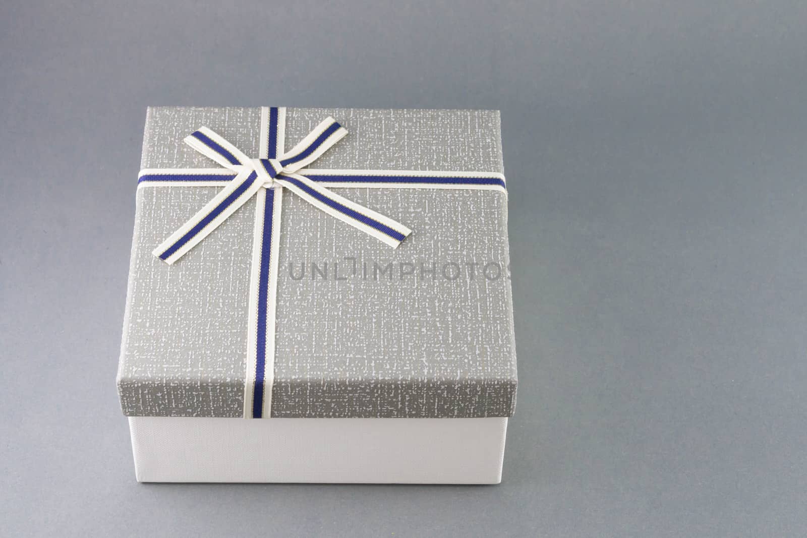 Grey gift box with ribbon on grey background, copy space