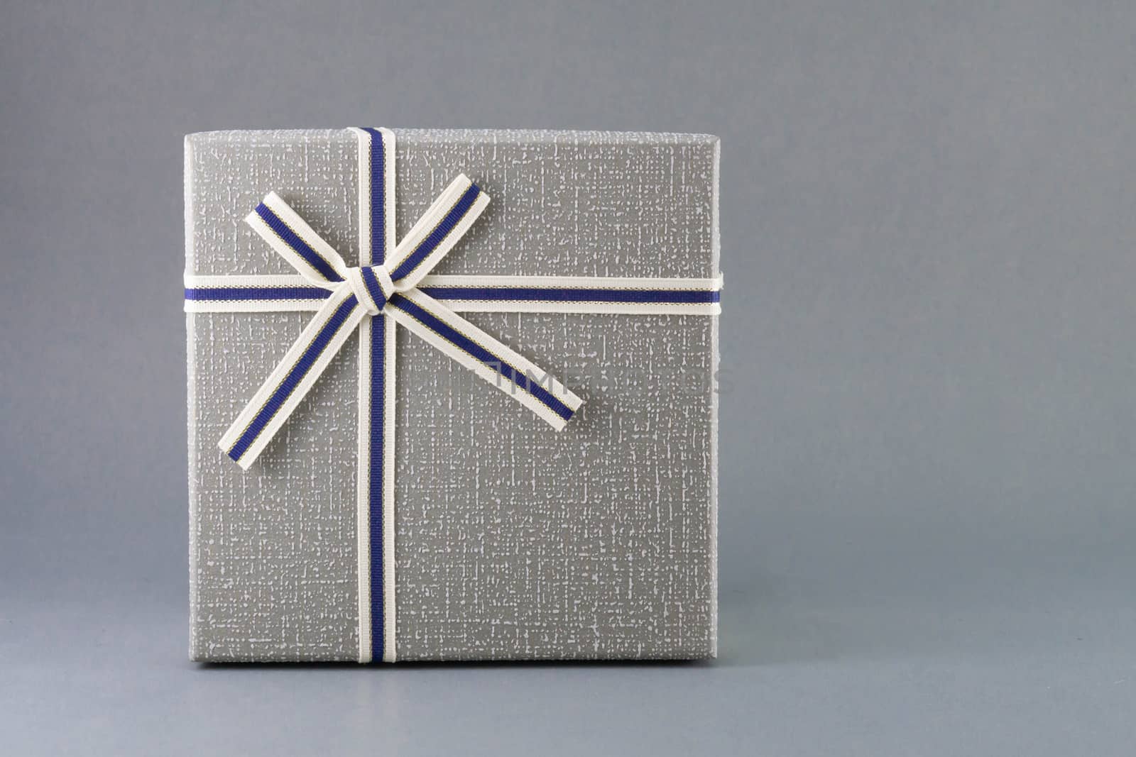 Grey gift box with ribbon on grey background, copy space