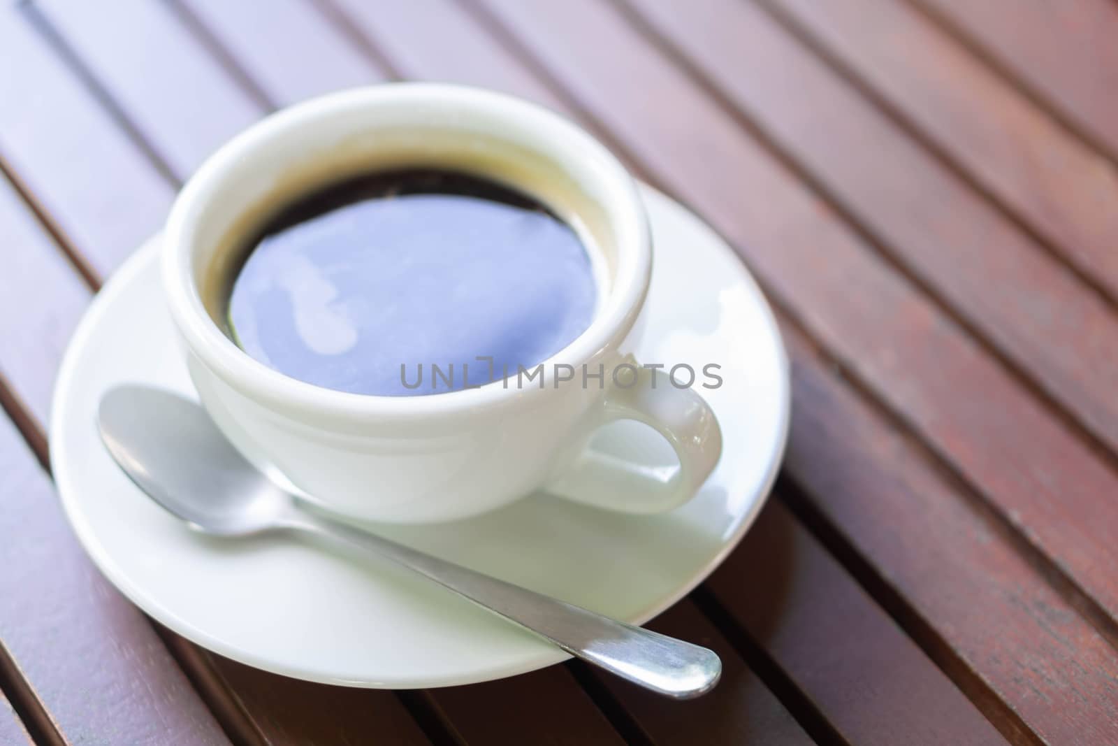 Closeup glass of hot americano coffee on wood table, selective focus, vintage tone