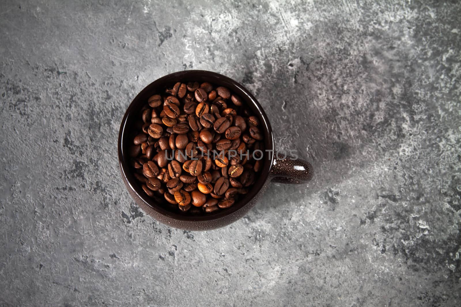 minimalism composition of a round brown ceramic Cup with coffee beans on a gray concrete background