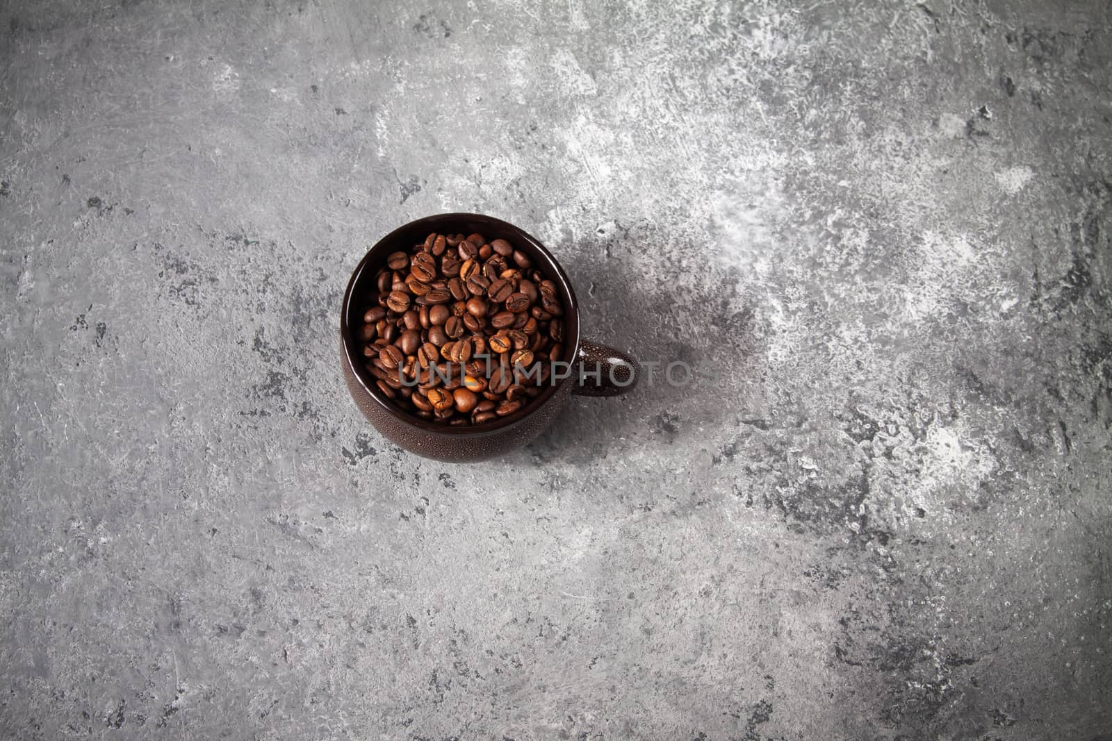 minimalism composition of a round brown ceramic Cup with coffee beans on a gray concrete background