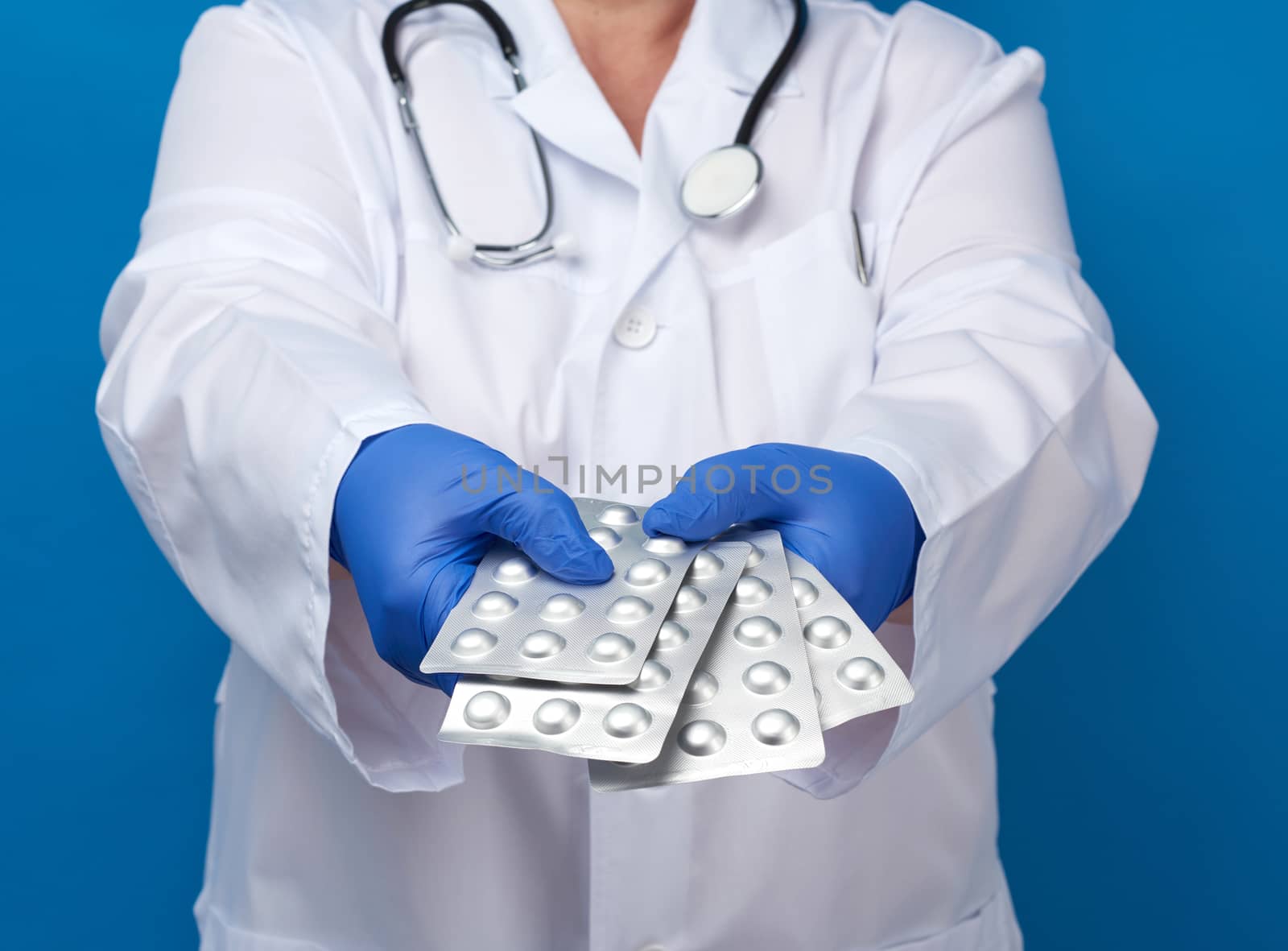 medic woman in white coat and blue latex gloves holds a pack of by ndanko