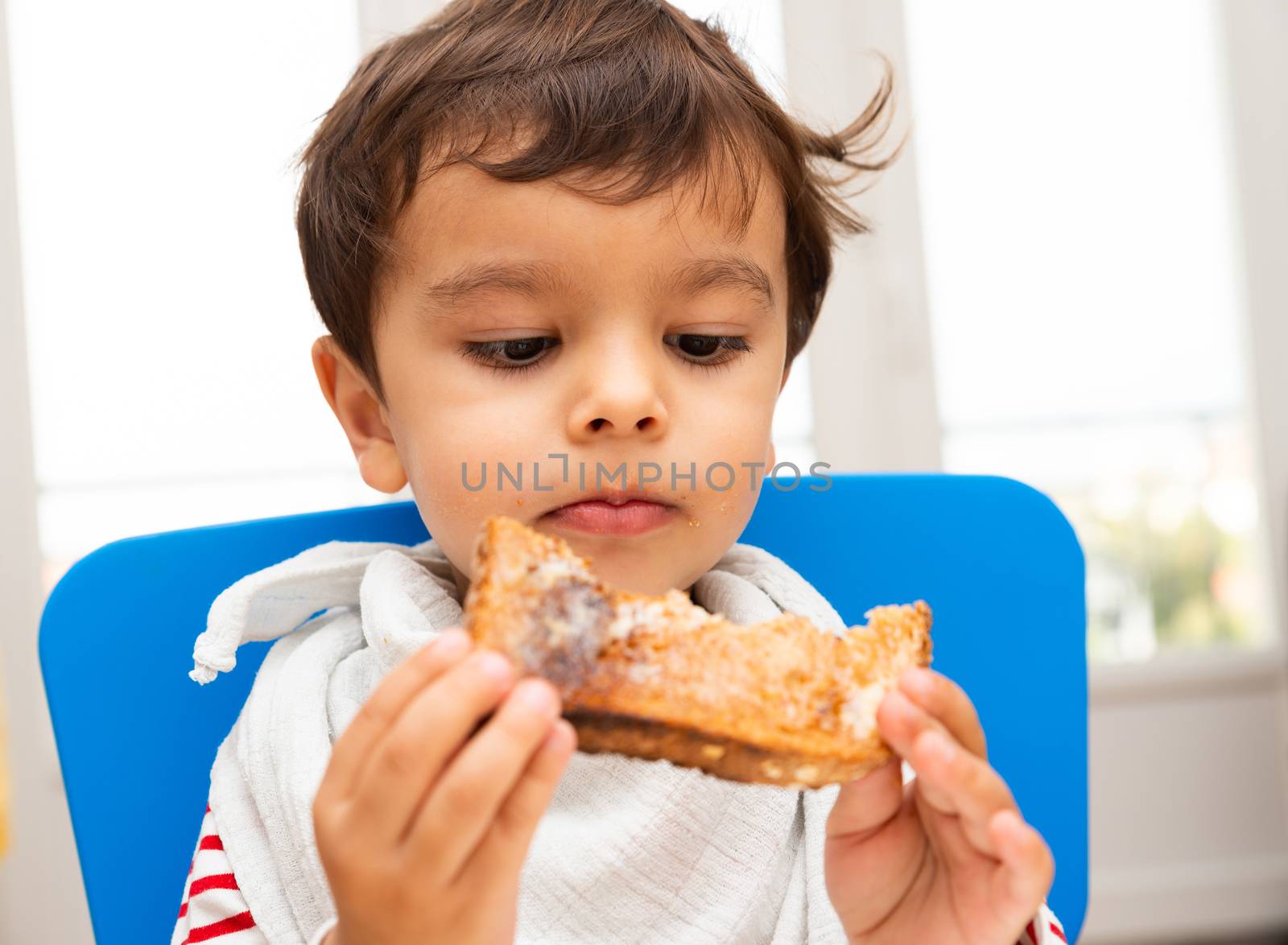 Toddler boy eating a toast with butter