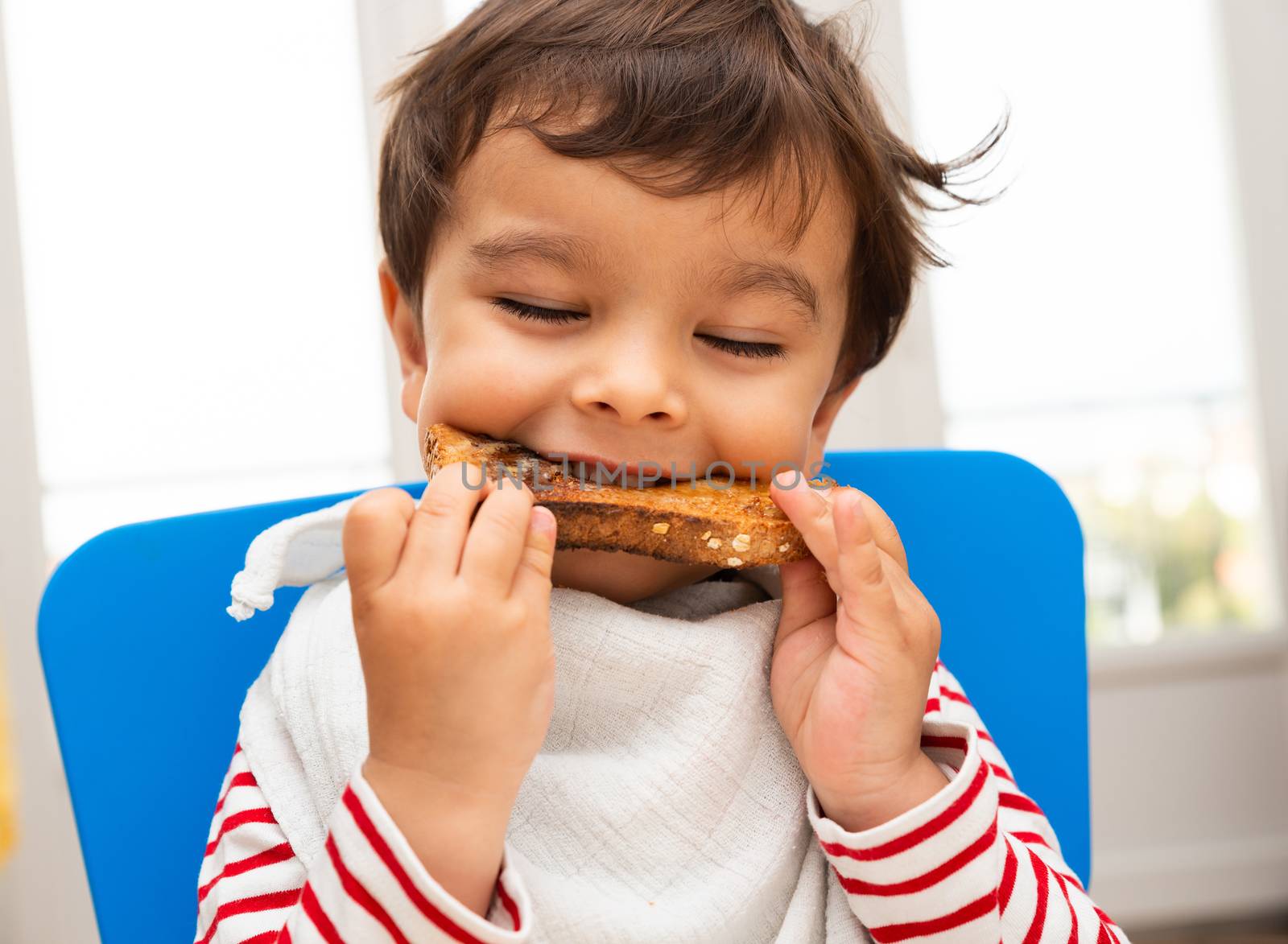 Toddler boy eating a toast with butter