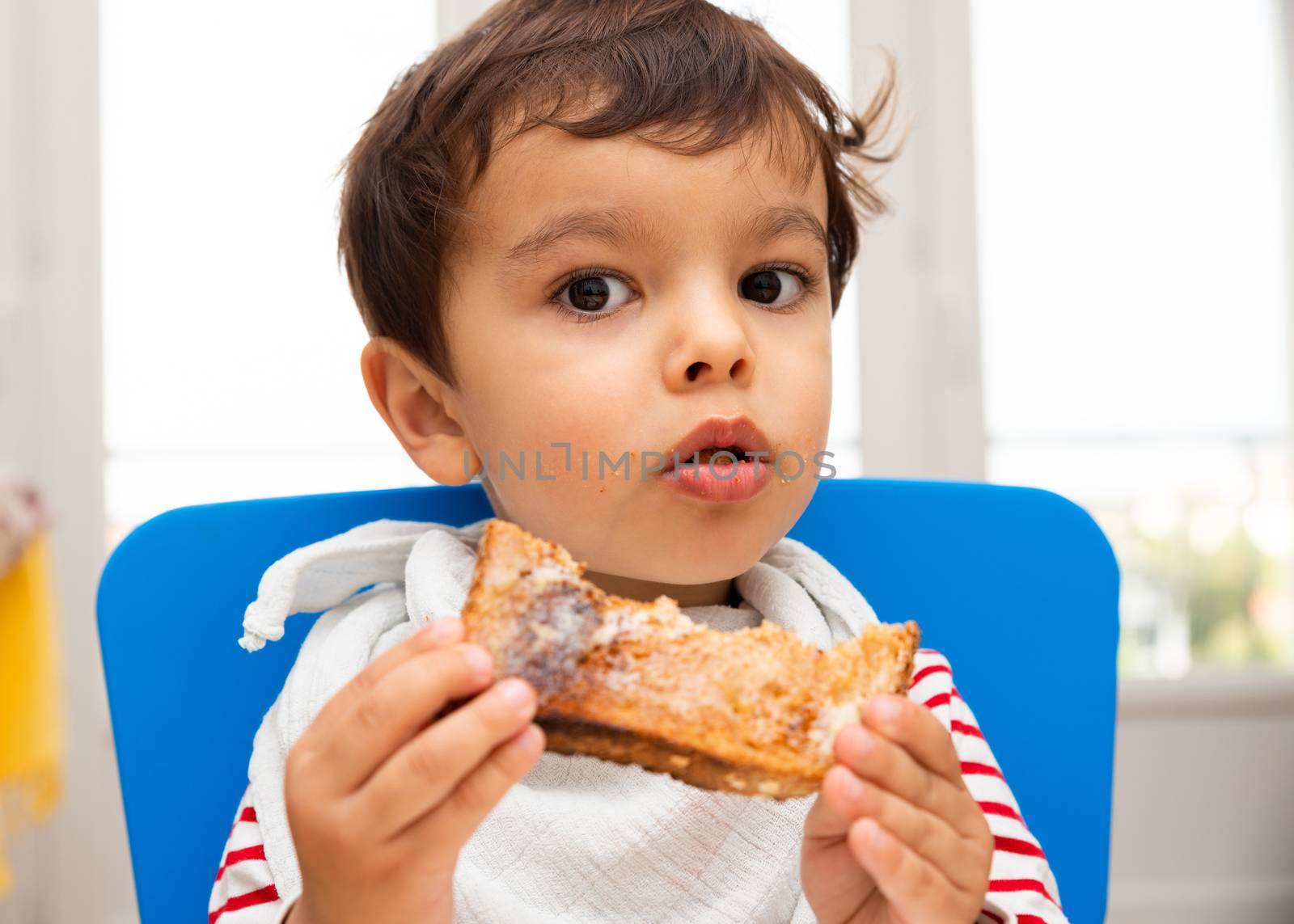 Toddler boy eating a toast with butter