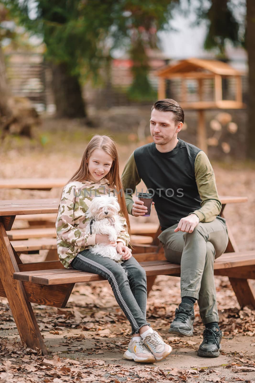 Father and daughter playing with dog outdoors by travnikovstudio