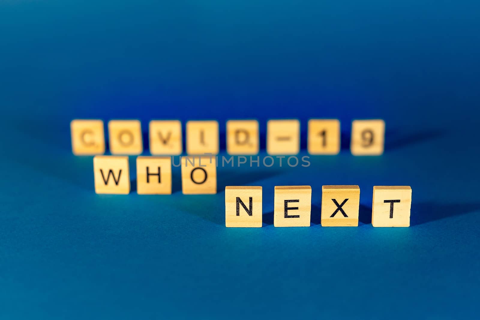 who's next the phrase is made of wooden letters on a blue background, blur on the background.