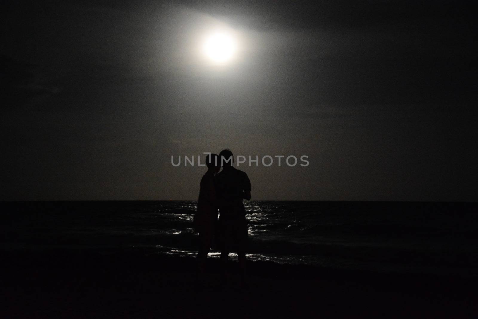 Loving couple look at the moon in mexico near the sea