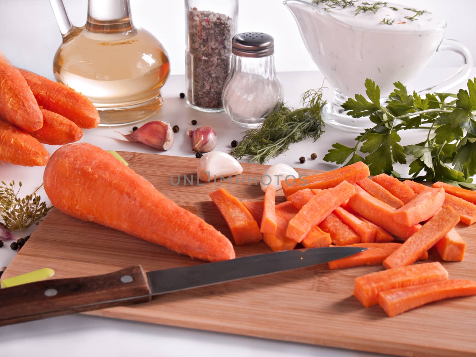 Carrots chopped on chopsticks surrounded by greenery, parsley, dill, garlic, pepper, vegetable oil in a bottle with a stopper, pepper and salt in jars, cream with greens in a glass, vegetable cutting knife, diet and healthy food, new Harvest of vegetables