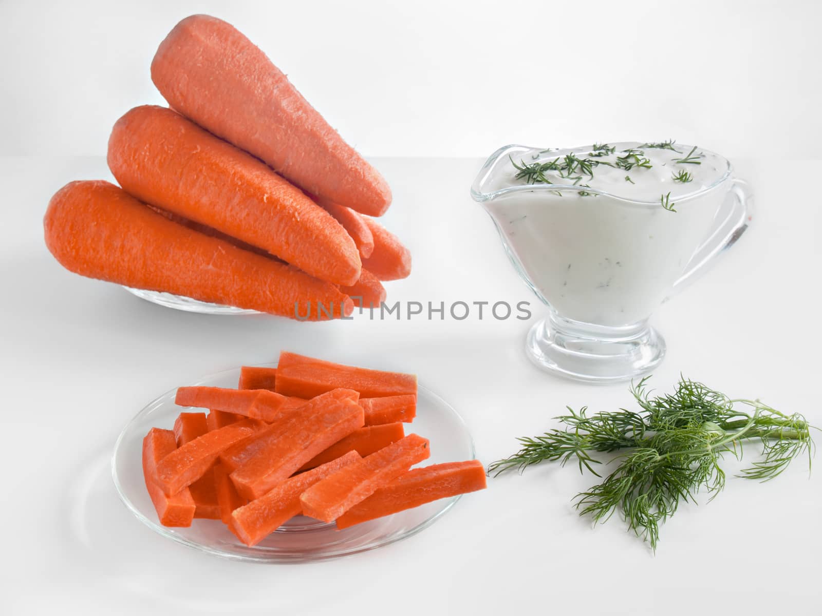 Carrot sticks, whole fresh carrots and sour cream sauce with herbs healthy dietary healthy food on a white background in glass plates and in a glass sauce boat