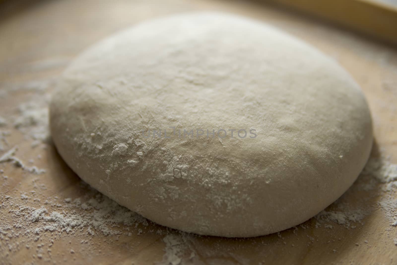 bread dough covered with flour on wooden pastry board