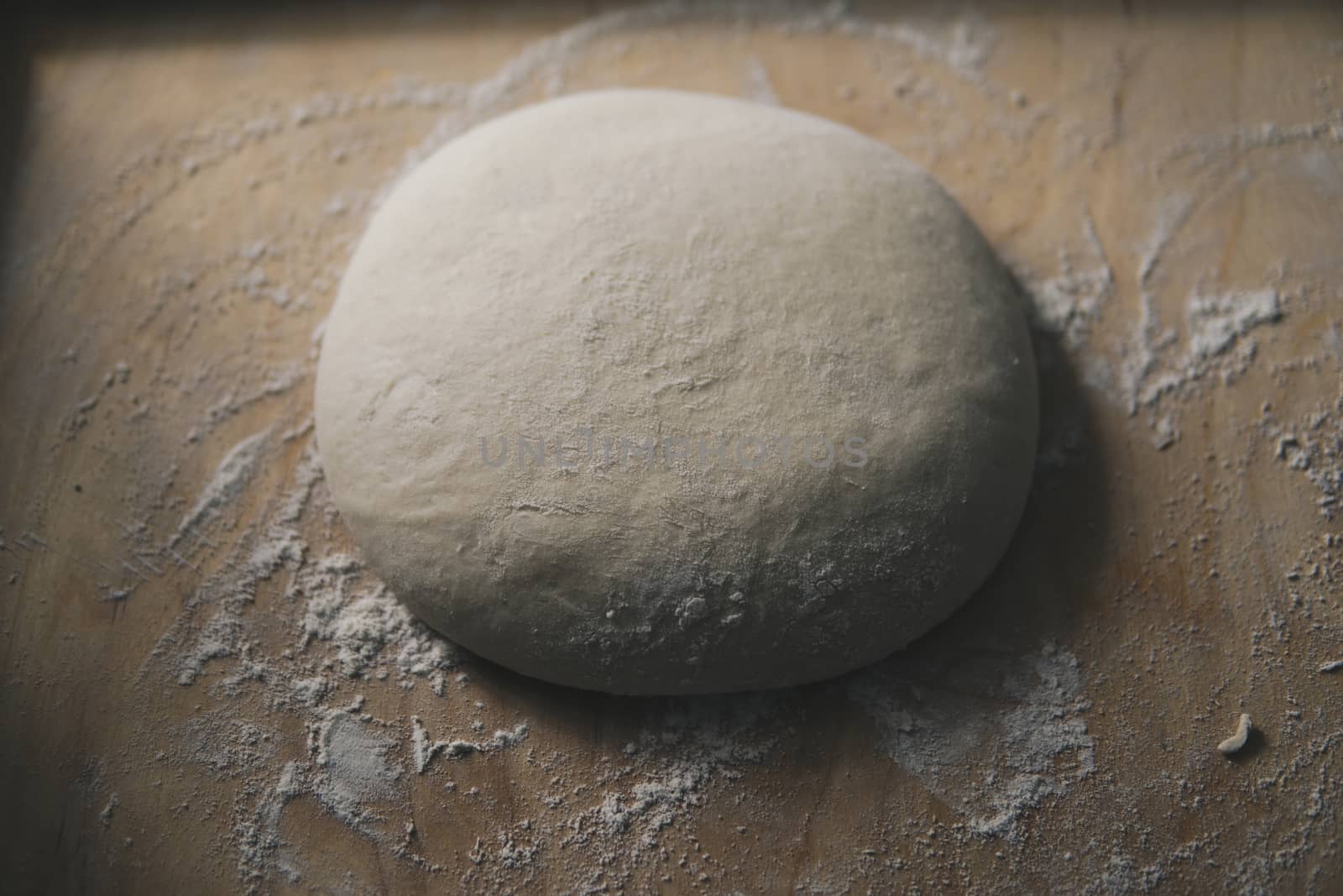 bread dough covered with flour on wooden pastry board