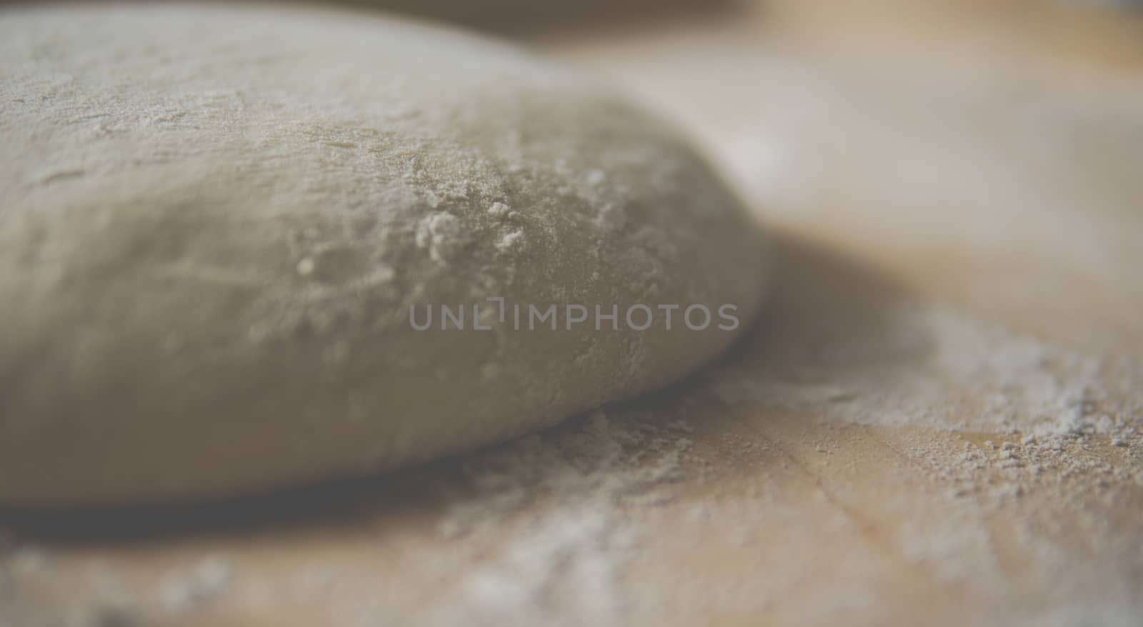 bread dough covered with flour on wooden pastry board