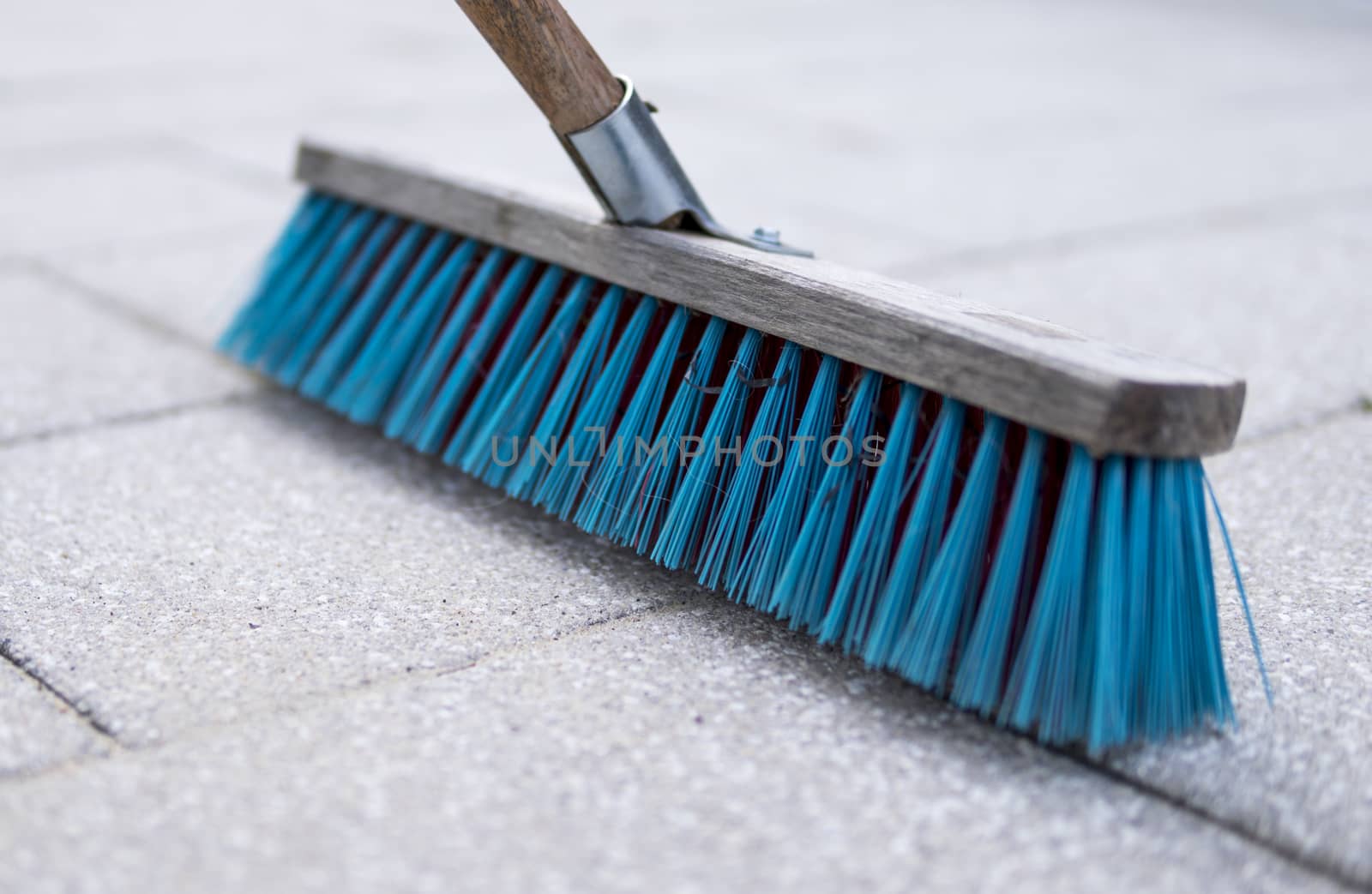 detail of blue brush used for cleaning pavemnet made from concrete stones