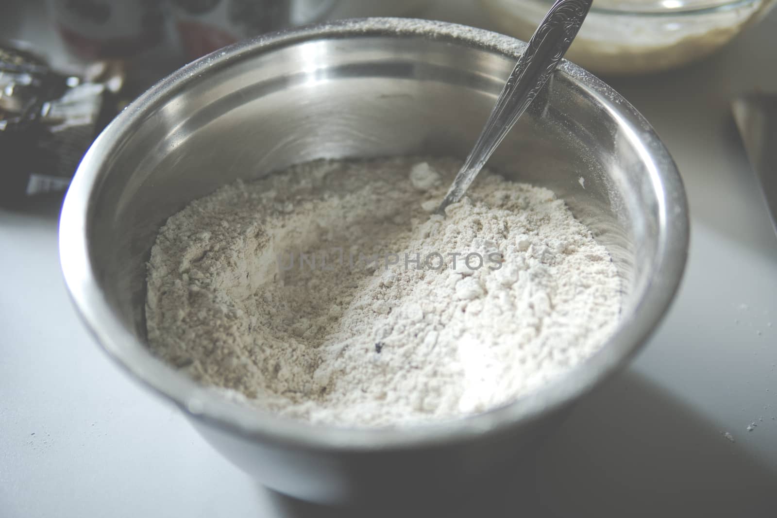 Flour inside of a metal bowl with a spoon