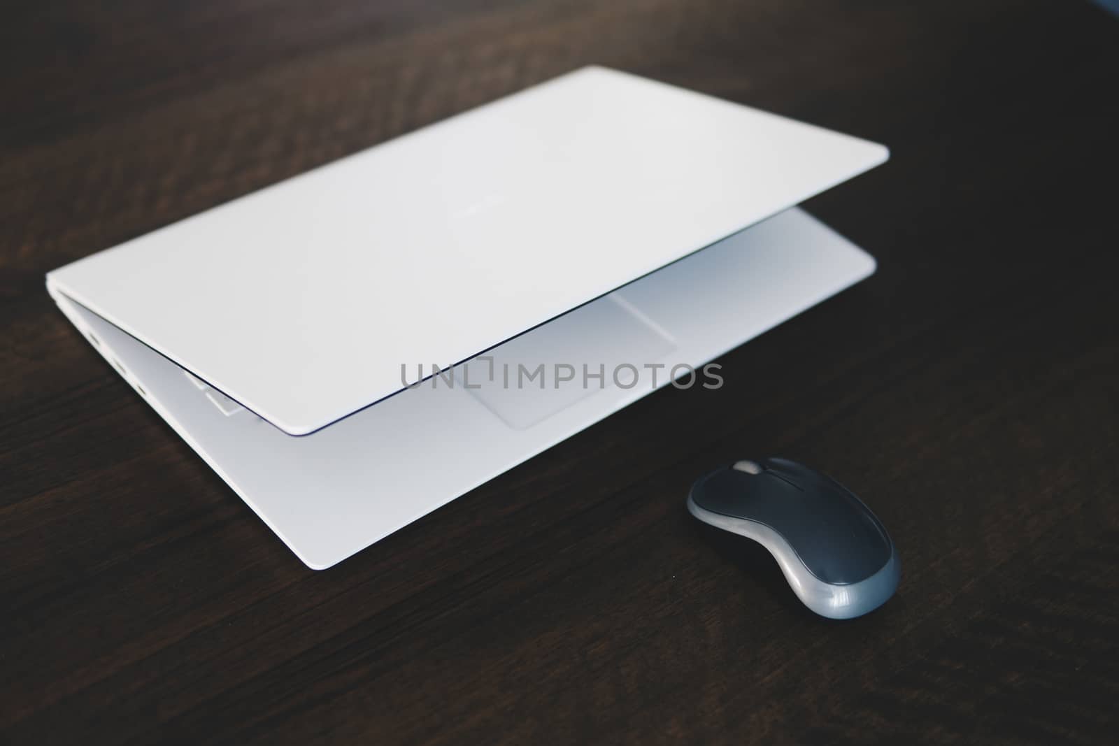 Composition of modern style white laptop with mouse on a dark wooden table