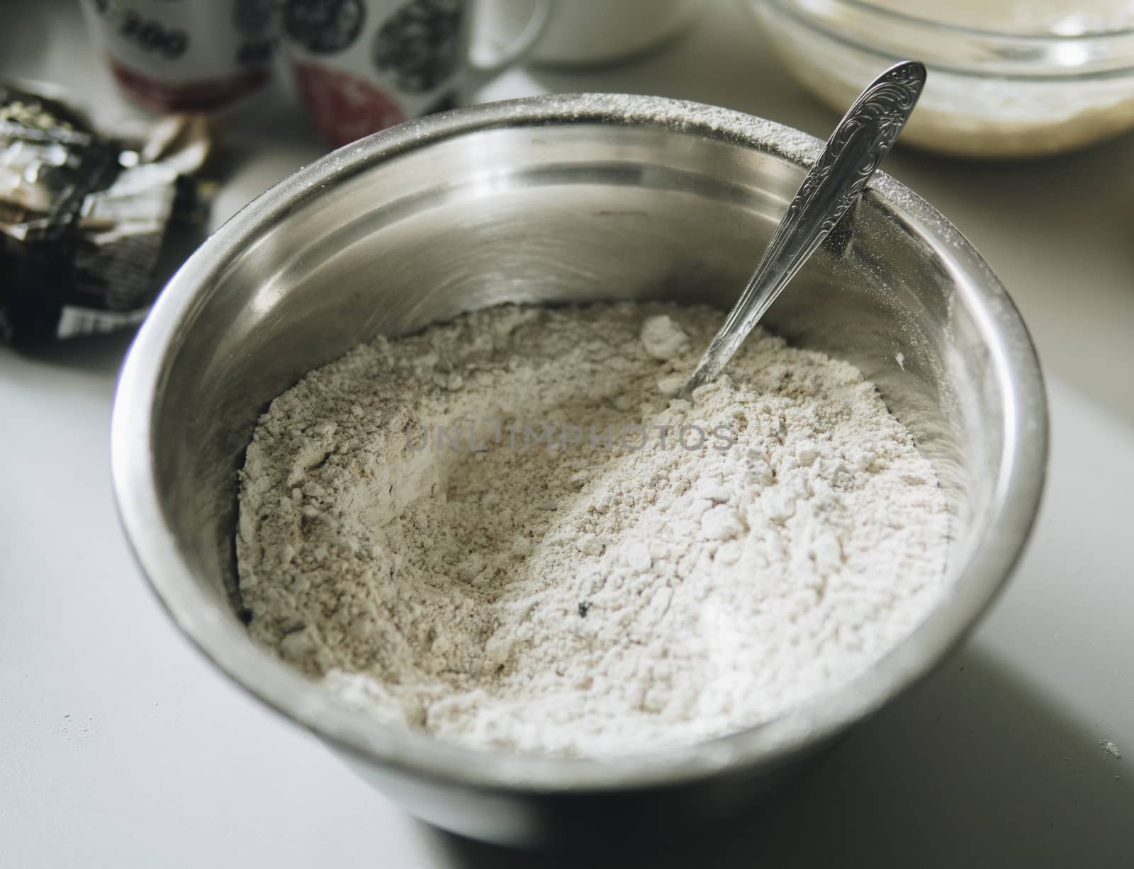 Flour inside of a metal bowl with a spoon