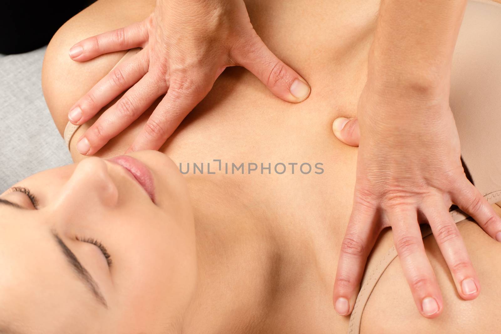 Close up top view of woman having kinesiological therapy. Hands applying pressure with thumbs on chest.