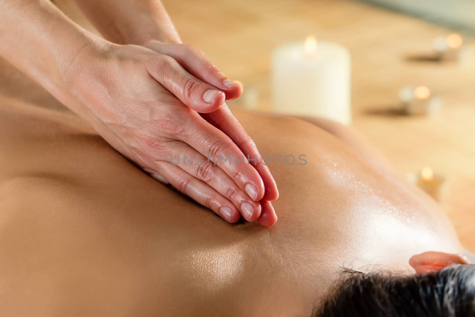 Close up detail of hands massaging spinal column on woman at candlelight.