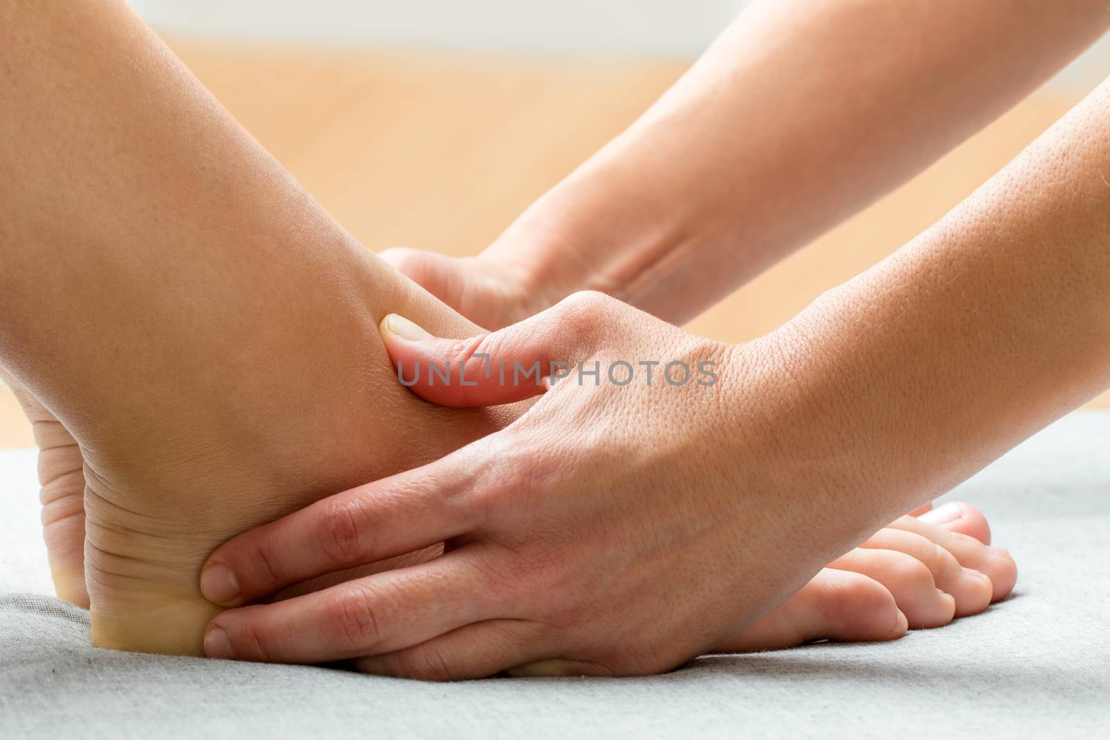 Close up of kinesiologist applying pressure with thumbs on female ankle.