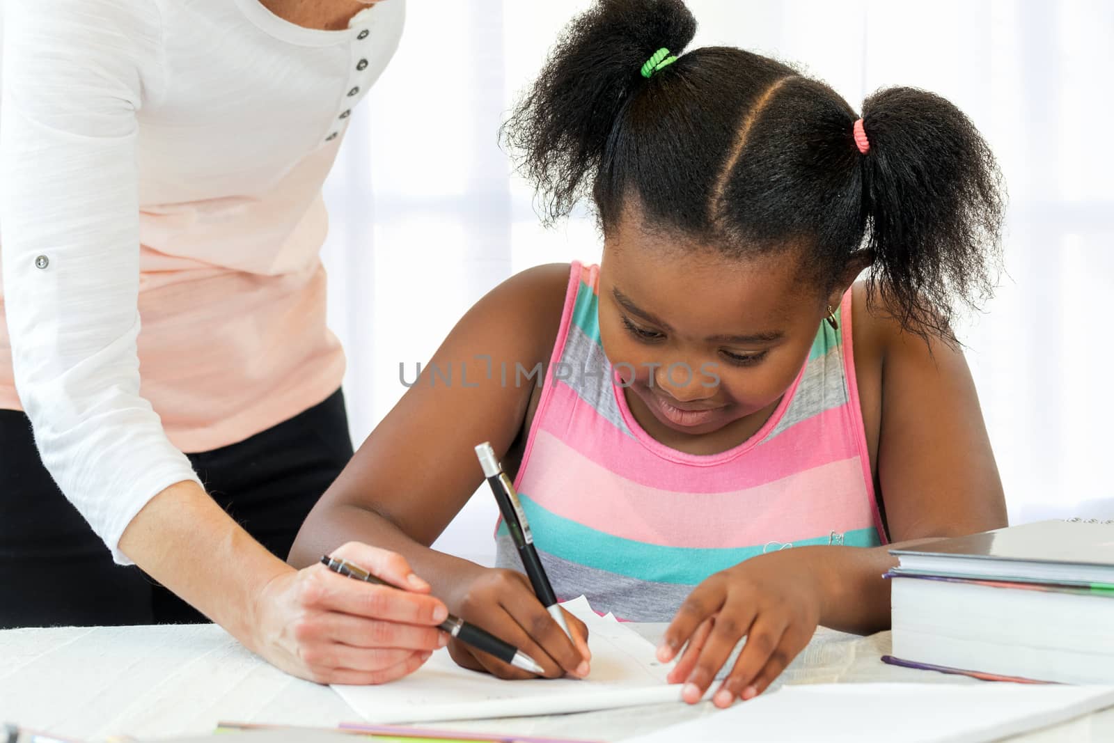 Caucasian teacher helping little black girl with maths. by karelnoppe
